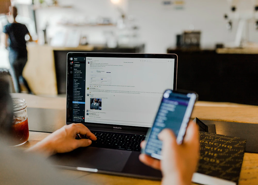 Person using a laptop and a smartphone at a café table