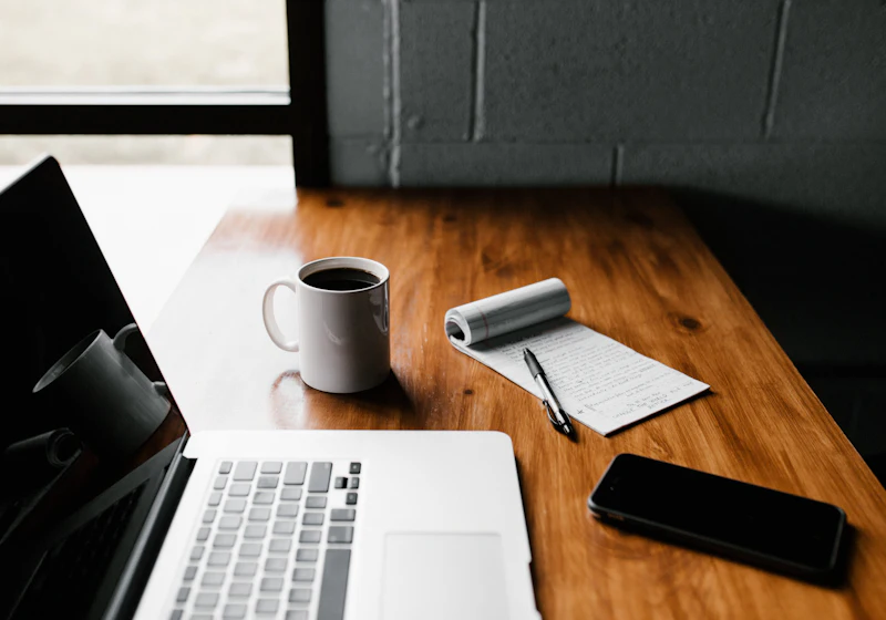 Laptop, coffee and notepad on a wooden desk