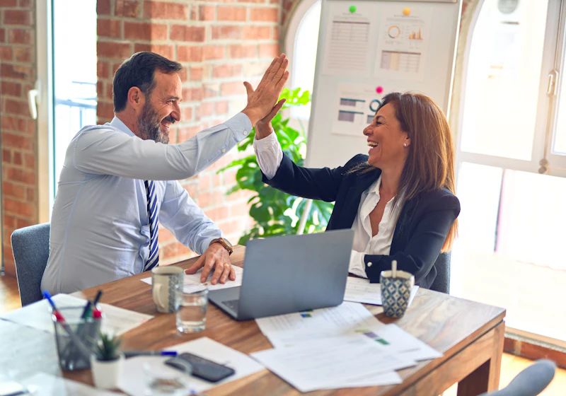 Two colleagues giving a high five at a desk